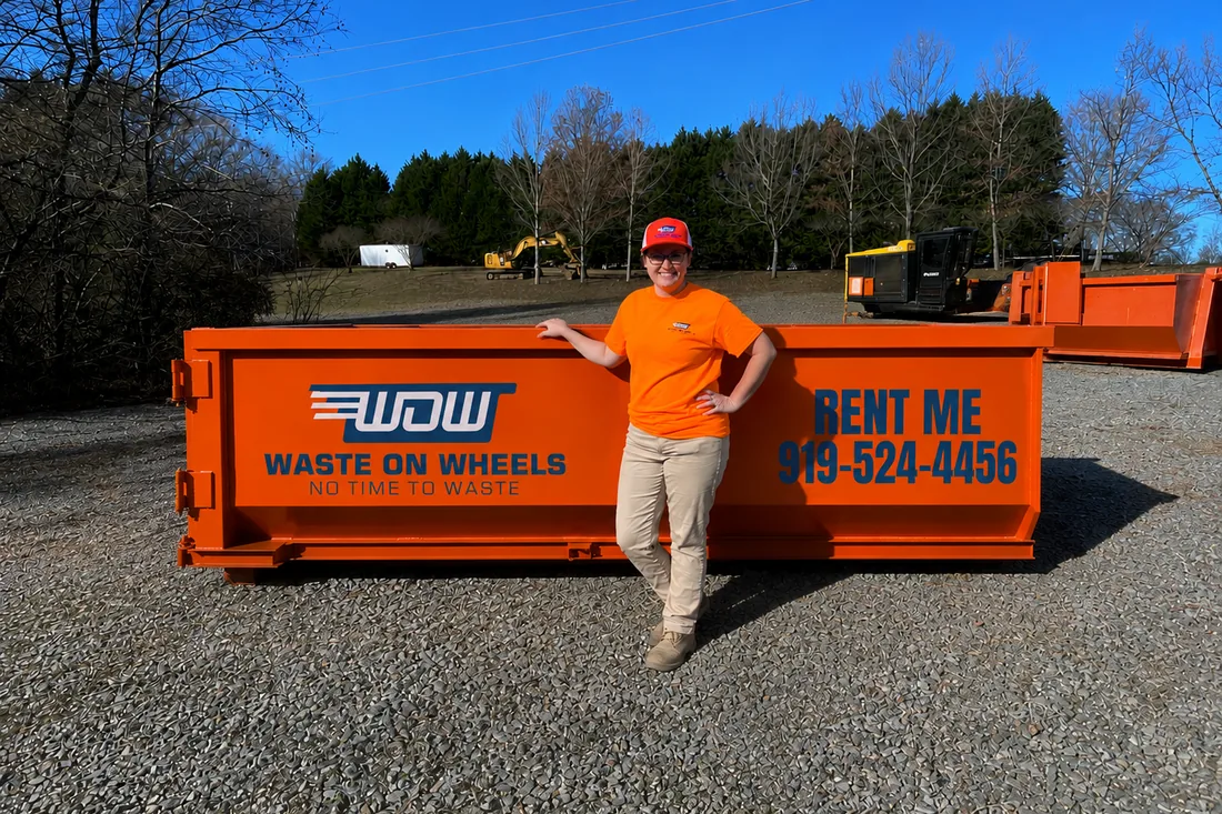 Waste On Wheels owner Logan standing beside a 10-yard roll-off dumpster for scale at the Willow Spring, NC yard