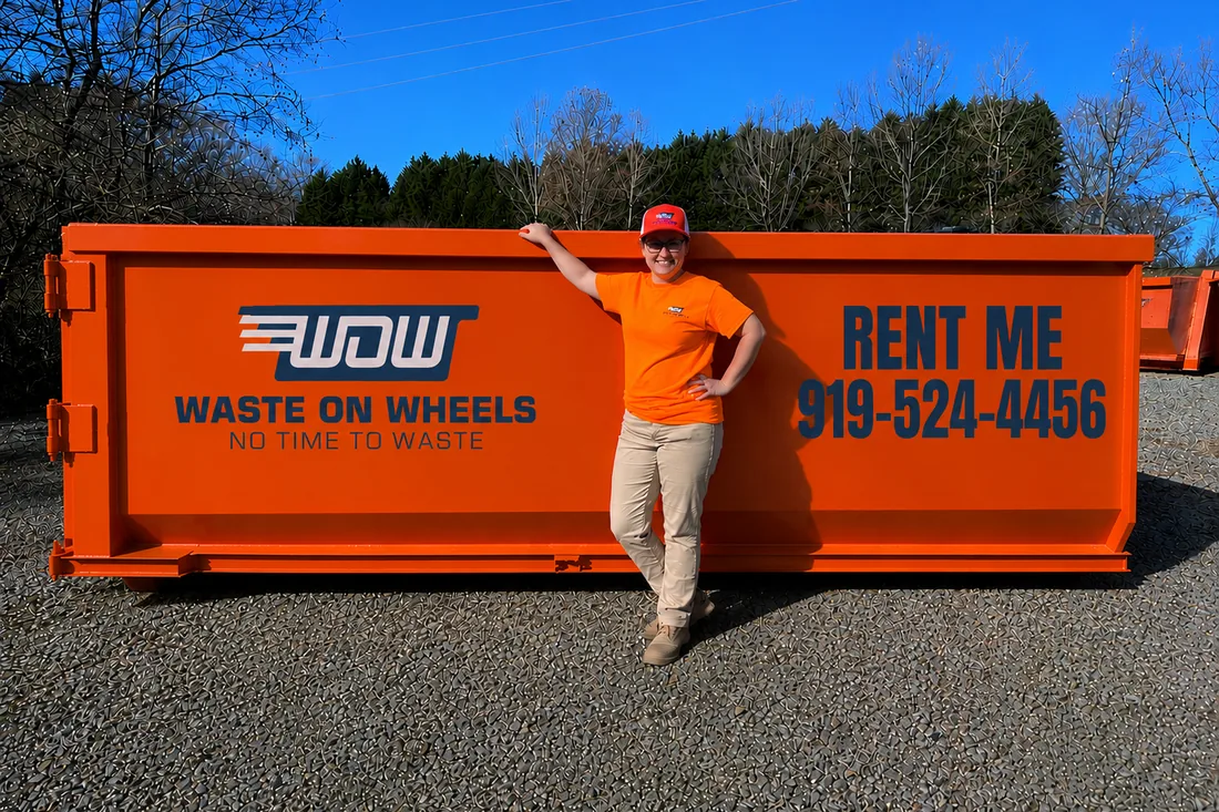 Waste On Wheels owner Logan standing beside a 20-yard roll-off dumpster for scale at the Willow Spring, NC yard