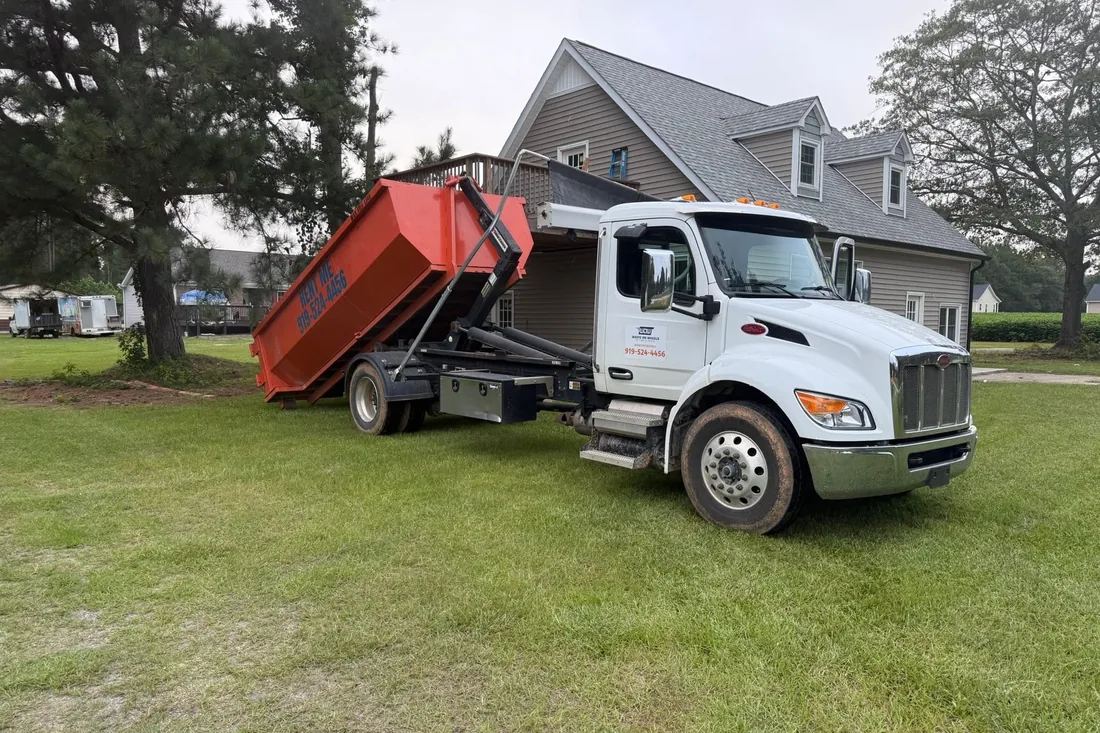 Waste On Wheels truck delivering a roll-off dumpster to a contractor job site